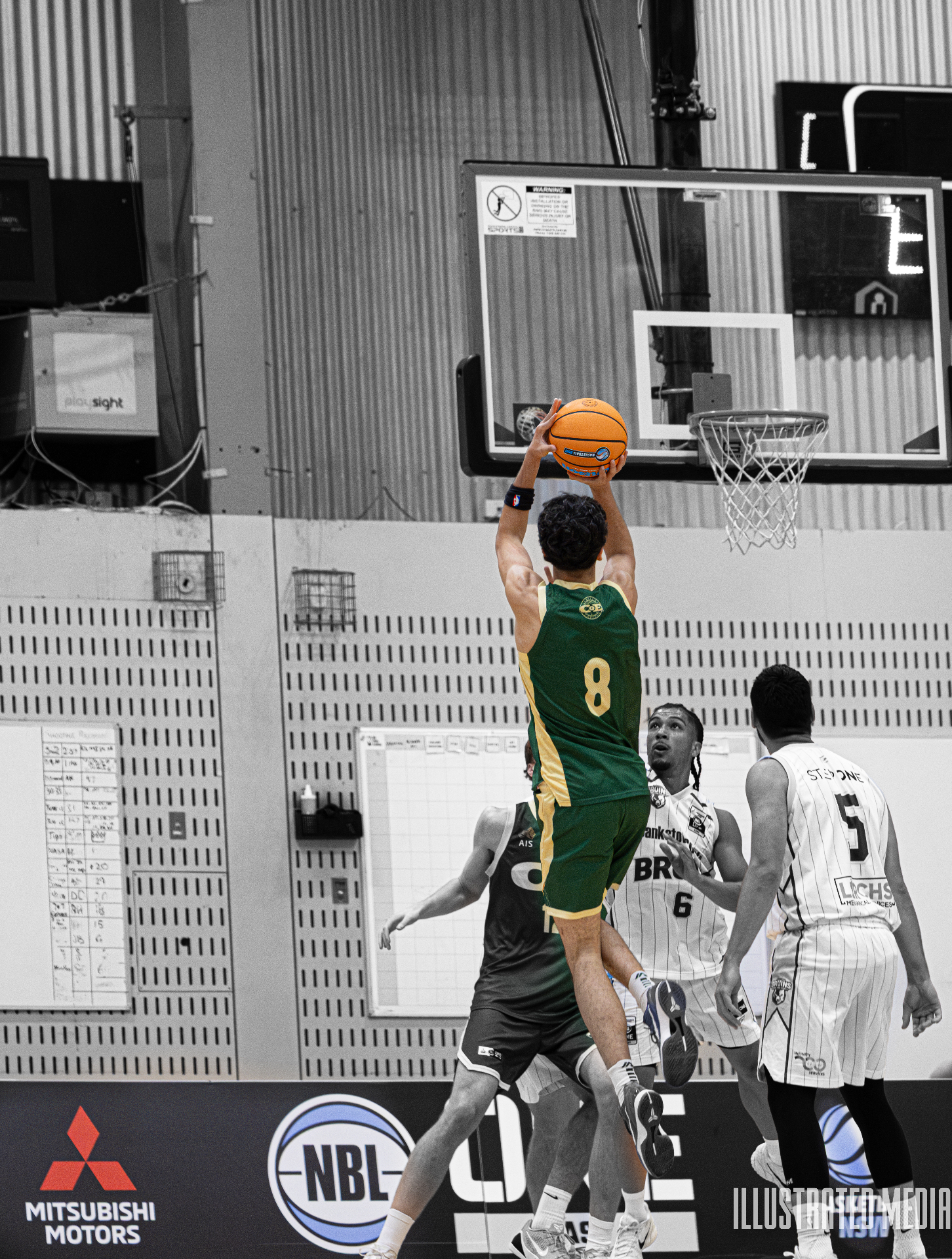 Basketball player rising into a jump shot near the rim during live game action.